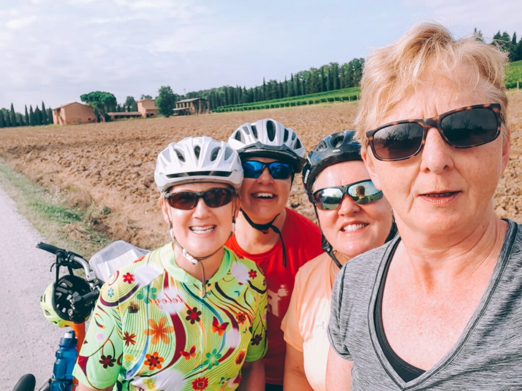 Group of smiling cyclists taking a break in the Umbrian countryside.