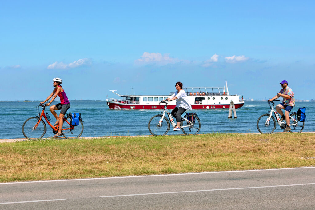 Cyclists on a coastal road overlooking the Adriatic Sea, Italy.